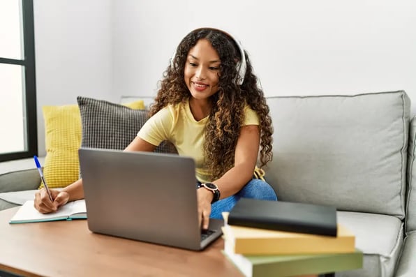 Estudiante latina asiste a una clase virtual desde su casa con el portátil