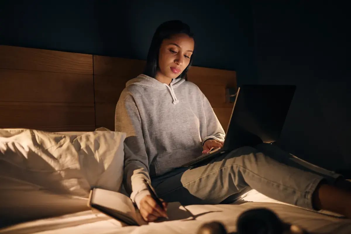 Estudiante organiza su tiempo de estudio con portátil y cuaderno en la noche