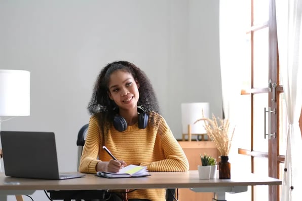 Estudiante con audífonos participa en una clase en línea desde el campus universitario